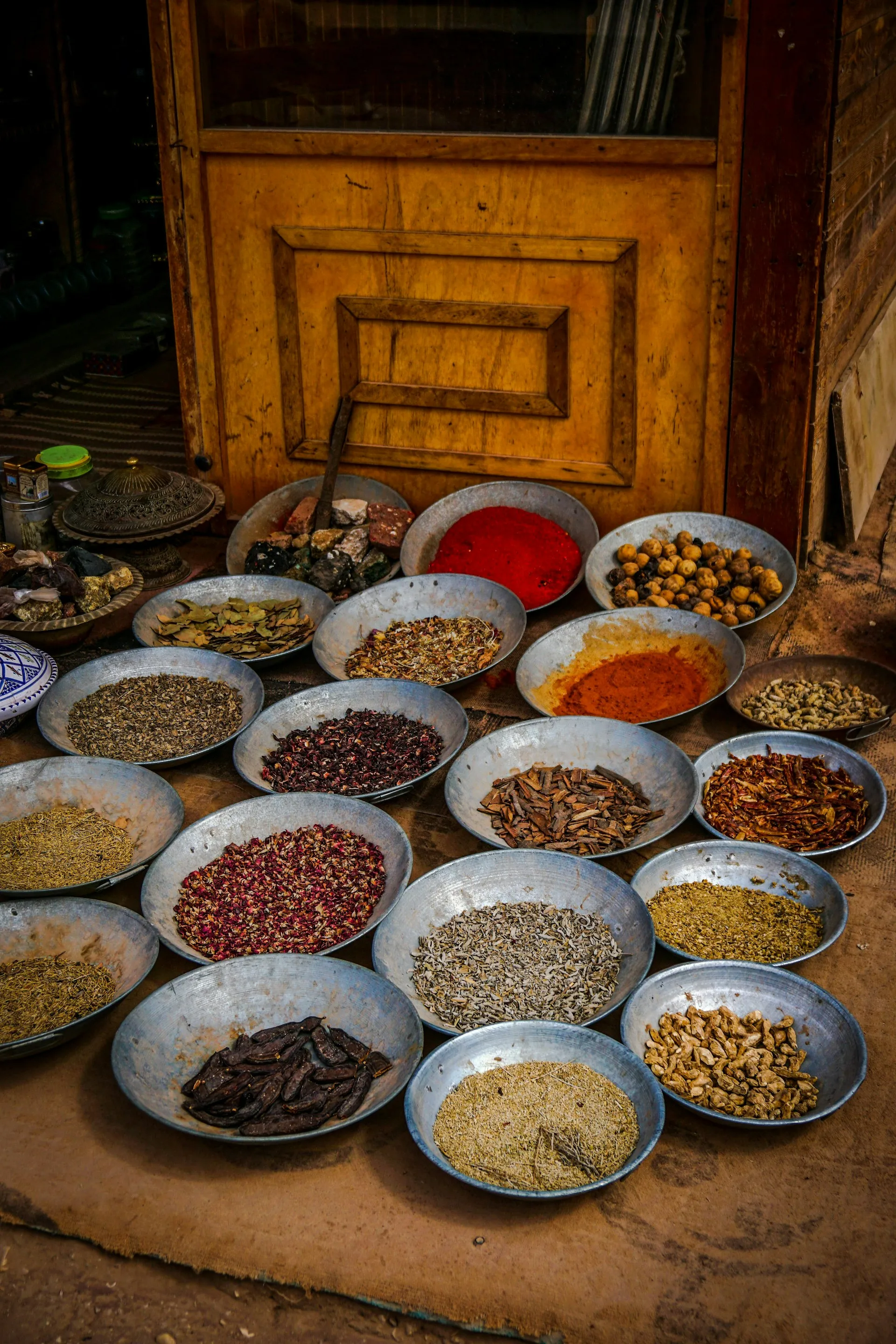 Colourful Indian spice powders arranged in metal bowls at a market.