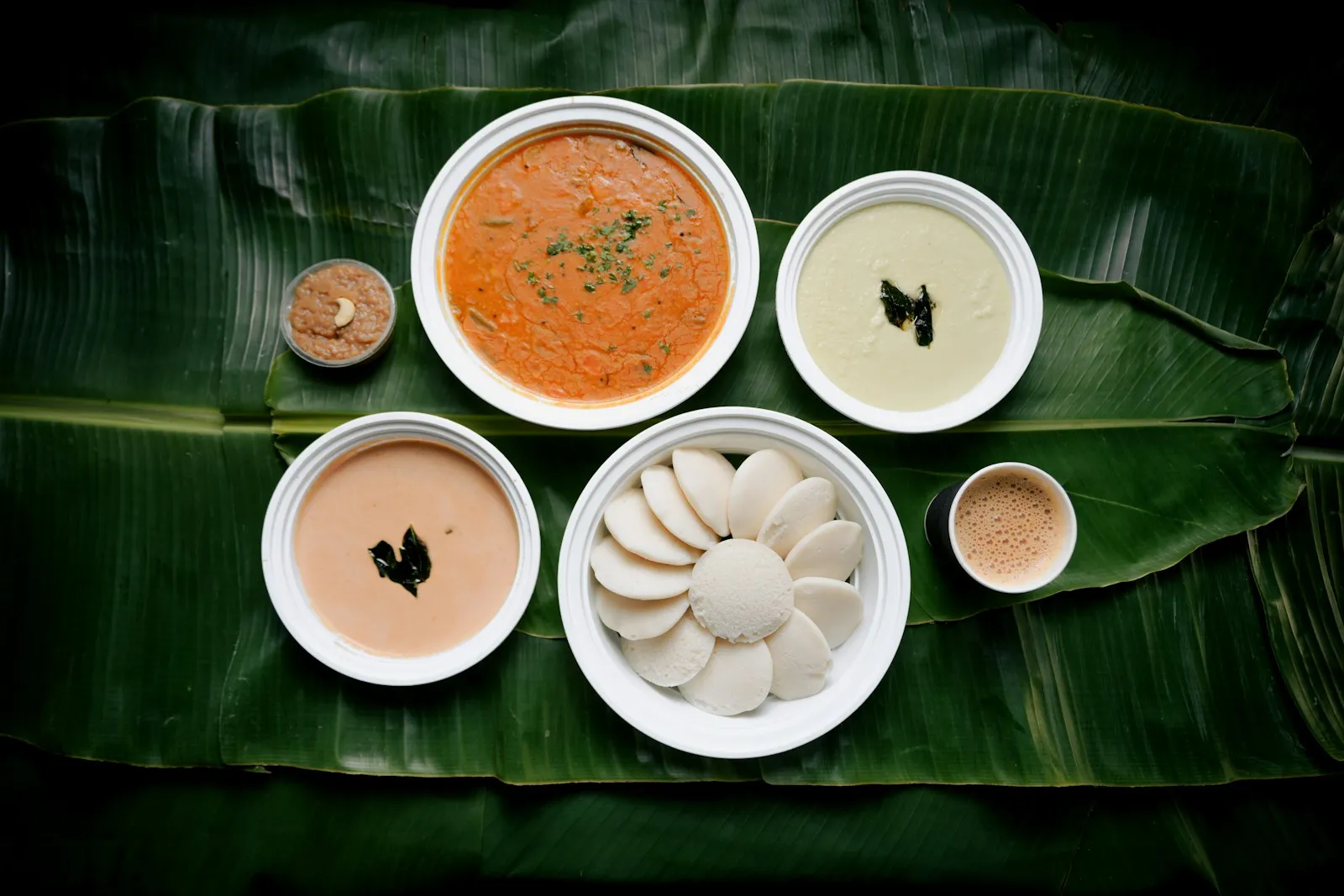 A traditional Kerala meal with idli, chutneys, and sambar served on a banana leaf.